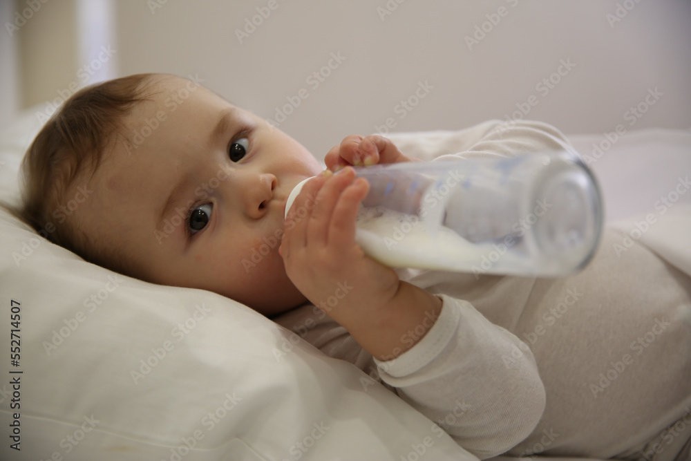 Cute little baby with bottle lying in comfortable crib. Bedtime Cute little baby with bottle lying in comfortable crib. Bedtime