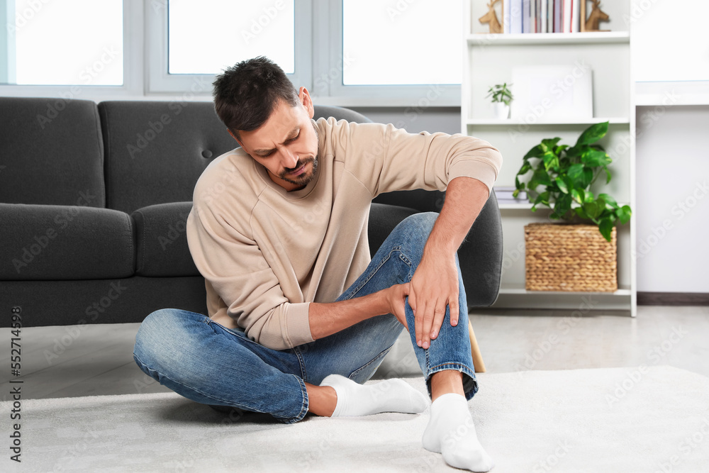Man suffering from leg pain at home