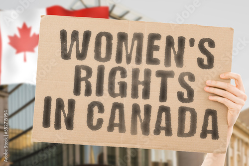 The phrase " Women's rights in Canada " is on a banner in men's hands with blurred background. Cheering. Community. Confidence. Courage. Crowd. Defend. Determination. Different. Diversity. Fight