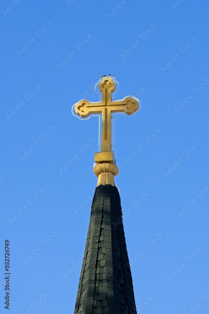 Cross on a steeple against a blue sky.