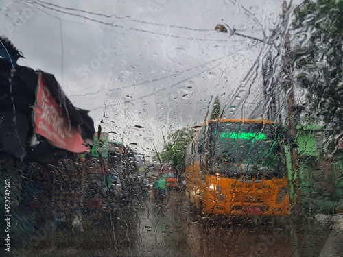 Jakarta, Indonesia in July 2022. The condition from inside a car, where the windshield of the car was raining and in front of the car there was a yellow school bus passing by