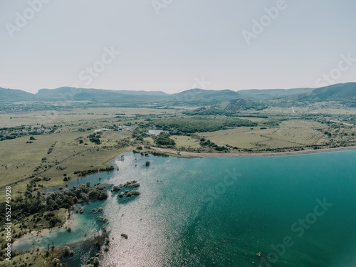 Aerial view on mountain lake. Drone over water reservoir at mountain valley covered with green spring forest. Beautiful view from above on smooth blue surface of mountain lake among highlands. Nobody
