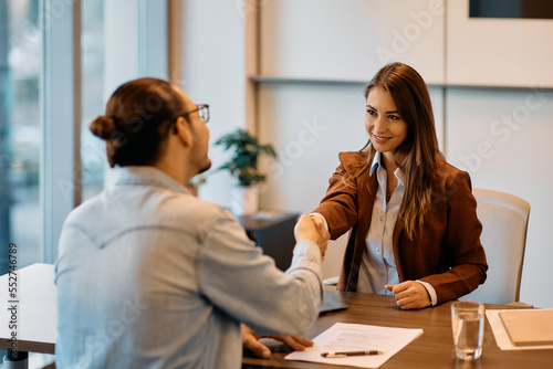 Fotografie Happy human resource manager handshaking with male candidate on job interview in office