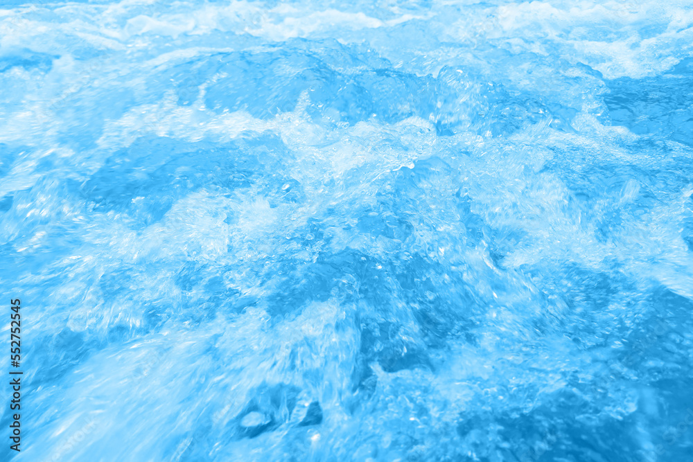 Defocus blurred transparent blue colored clear calm water surface texture with splashes and bubbles. Trendy abstract nature background. Water waves in sunlight with copy space. Blue watercolor shining