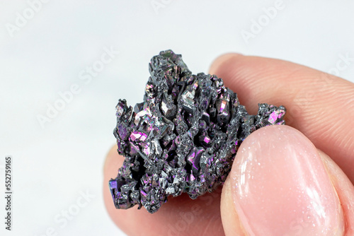 Woman hand holding shiny black Carborundum crystal (Moissanite or Silicon Carbide) on light background close up. photo