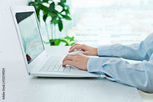 Close-up of businesswoman hand using a laptop on desk