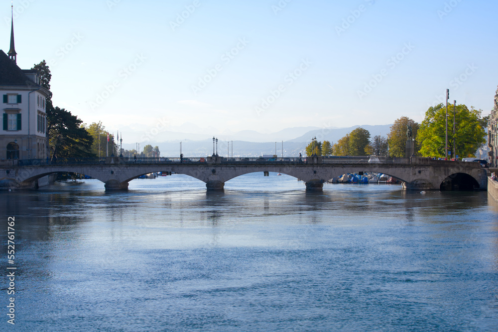 Fototapeta premium Beautiful cityscape of the old town of Zürich with Limmat River in the foreground and Minster Bridge in the back on a sunny late summer morning. Photo taken September 22nd, 2022, Zurich, Switzerland.
