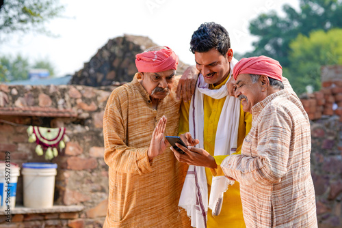Three Indian villagers watching some detail in smartphone.