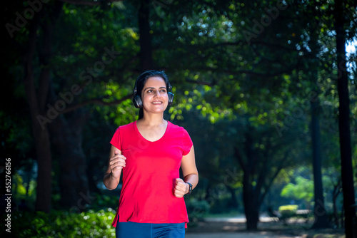 young indian woman with earphones listening music during jogging at park. © PRASANNAPIX