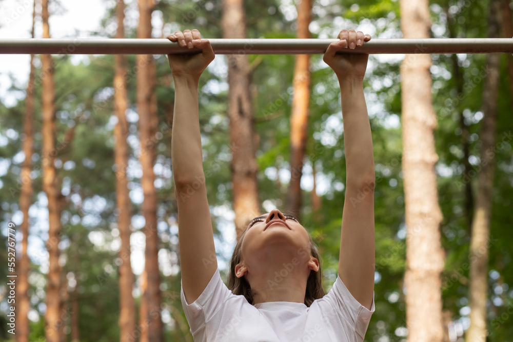 Fototapeta premium teenager girl pulls up on the horizontal bar in a street gym