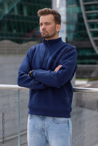 Obraz na płótnie City portrait of handsome hipster guy with beard wearing blue blank hoodie or sweatshirt with space for your logo or design. Mockup for print w salonie