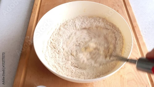 Add flour to the dough, sift and mix well in a white bowl on a wooden background. Step 4.