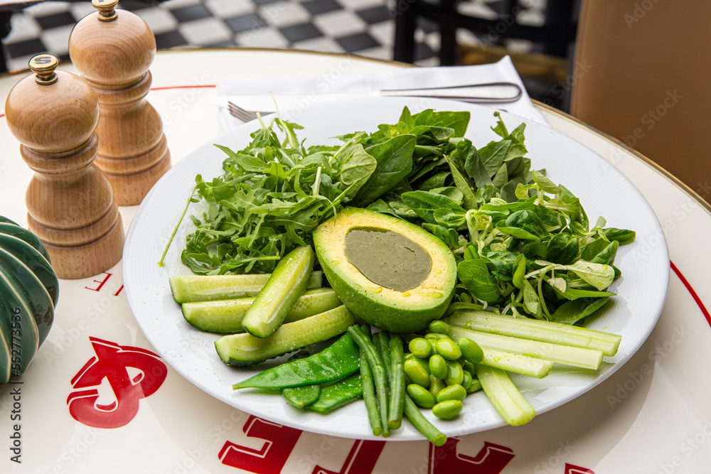 Green plate with lettuce, arugula, avocado, cucumbers and green peas Green plate with lettuce, arugula, avocado, cucumbers and green peas