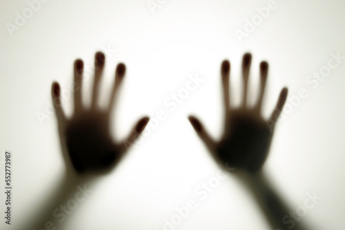 Blurred shadows of hands behind frosted glass, concept of nightmares, horror, domestic violence