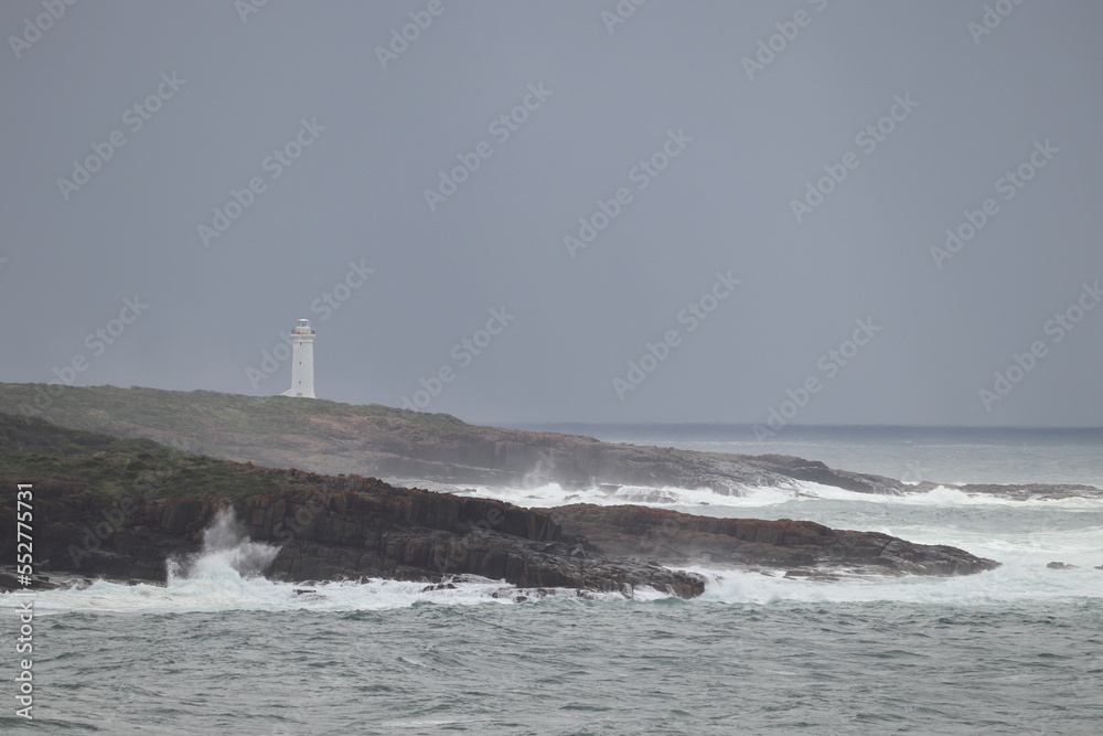 Port Stephens Light house at the end of Shark Island near Fingal Bay, with waves crashing on the rocks