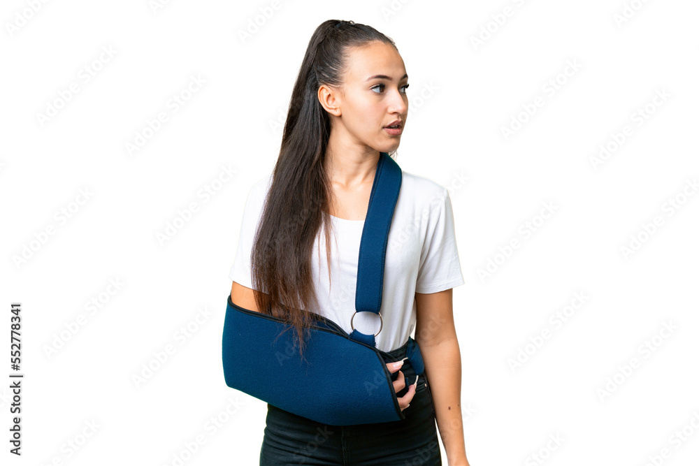 Young Arabian woman with broken arm and wearing a sling over isolated chroma key background looking to the side Young Arabian woman with broken arm and wearing a sling over isolated chroma key background looking to the side