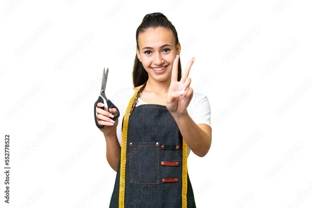 Young Seamstress woman over isolated chroma key background smiling and showing victory sign Young Seamstress woman over isolated chroma key background smiling and showing victory sign