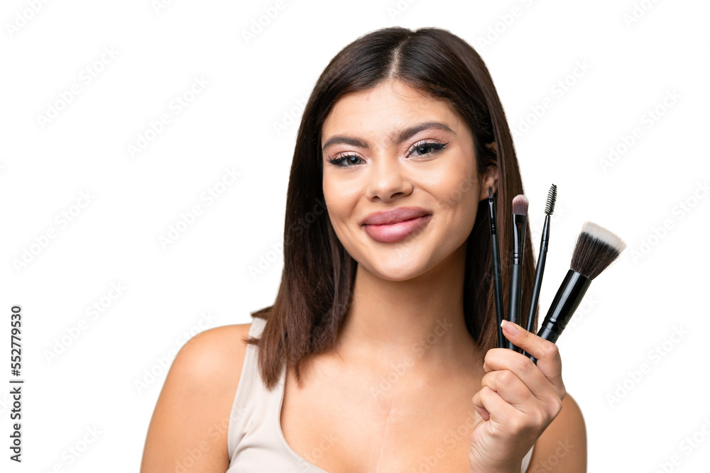 Young Russian woman with rainproof coat and umbrella over isolated chroma key background holding makeup brush Young Russian woman with rainproof coat and umbrella over isolated chroma key background holding makeup brush