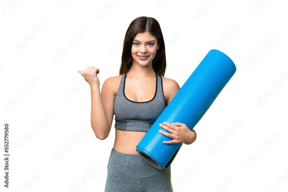 Young sport woman going to yoga classes while holding a mat over isolated chroma key background pointing to the side to present a product Young sport woman going to yoga classes while holding a mat over isolated chroma key background pointing to the side to present a product