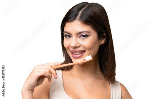 Young Russian woman with rainproof coat and umbrella over isolated chroma key background with a toothbrush and happy expression