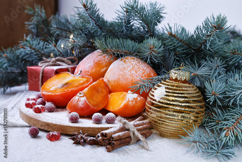 Christmas composition with fir branches, snow-covered persimmons and Christmas decorations