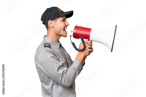 Young security man over isolated background shouting through a megaphone