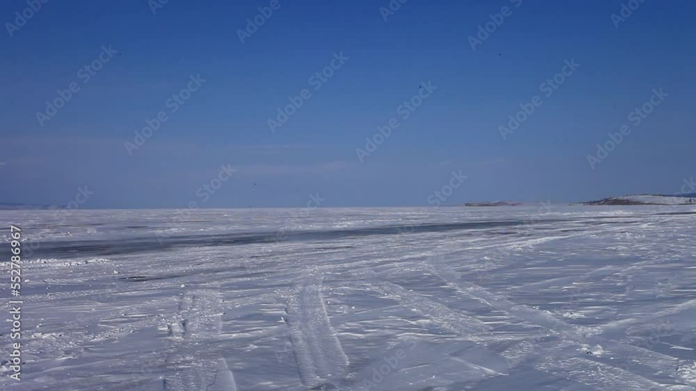 Baikal Lake in winter. Ice road along the Small Sea to Olkhon Island. Tourists drive across the snow-covered ice in a traditional off-road vehicle, which local drivers call Loaf. Winter travel concept Baikal Lake in winter. Ice road along the Small Sea to Olkhon Island. Tourists drive across the snow-covered ice in a traditional off-road vehicle, which local drivers call Loaf. Winter travel concept
