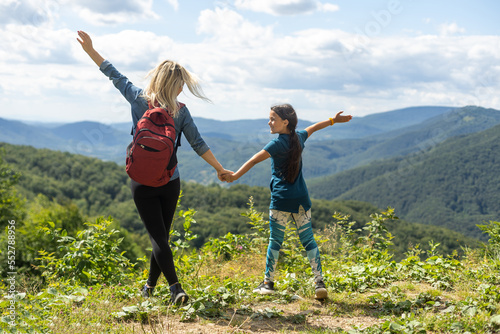 Mother and child with a backpack enjoying in the mountains.The concept of family travel, adventure, and tourism. Lifestyle and hiking autumn vacations outdoor. Back view.