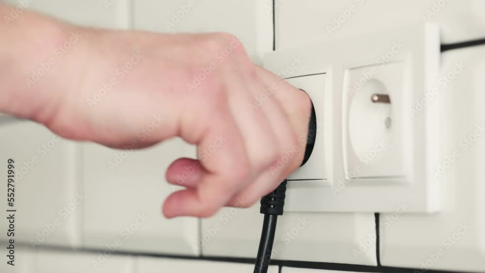 Human hand plugging cable to socket for electricity connection. Safe voltage usage from energy network