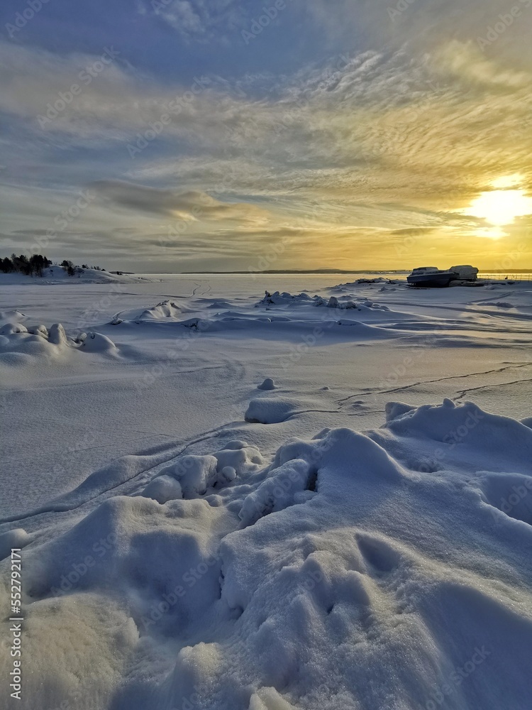 Winter sunset on frozen and snow-covered White sea. Kandalaksha, Kola Peninsula, Murmansk region.