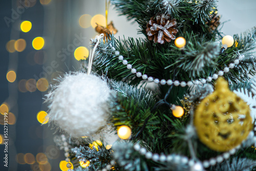Close-up of beautiful decorated Christmas tree. White ball, beads. Bokeh lights of luminous garland.