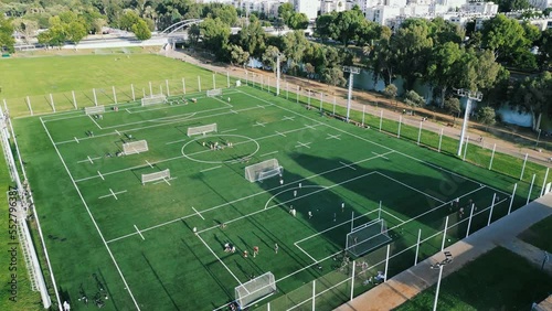 Soccer training on green field. Kid Football players running around the football field. Children game workout. Preparation for the match. Aerial shot with a drone from a altitude