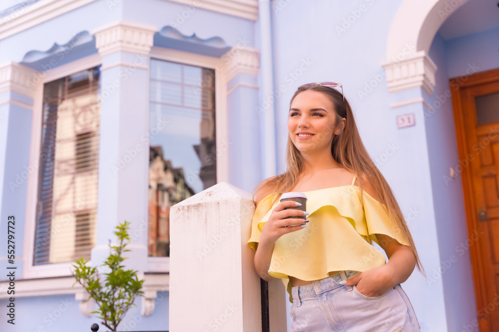 Portrait of young blonde in a neighborhood with houses with colorful facades, with a cafe in her home Portrait of young blonde in a neighborhood with houses with colorful facades, with a cafe in her home