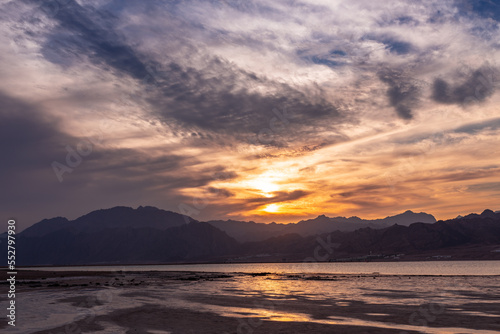 Picturesque sunset landscape on beach with coloful clouds and mountains in background, Dahab, Egypt