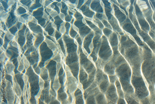 Sand underwater with sun glare from shallow water ripples
