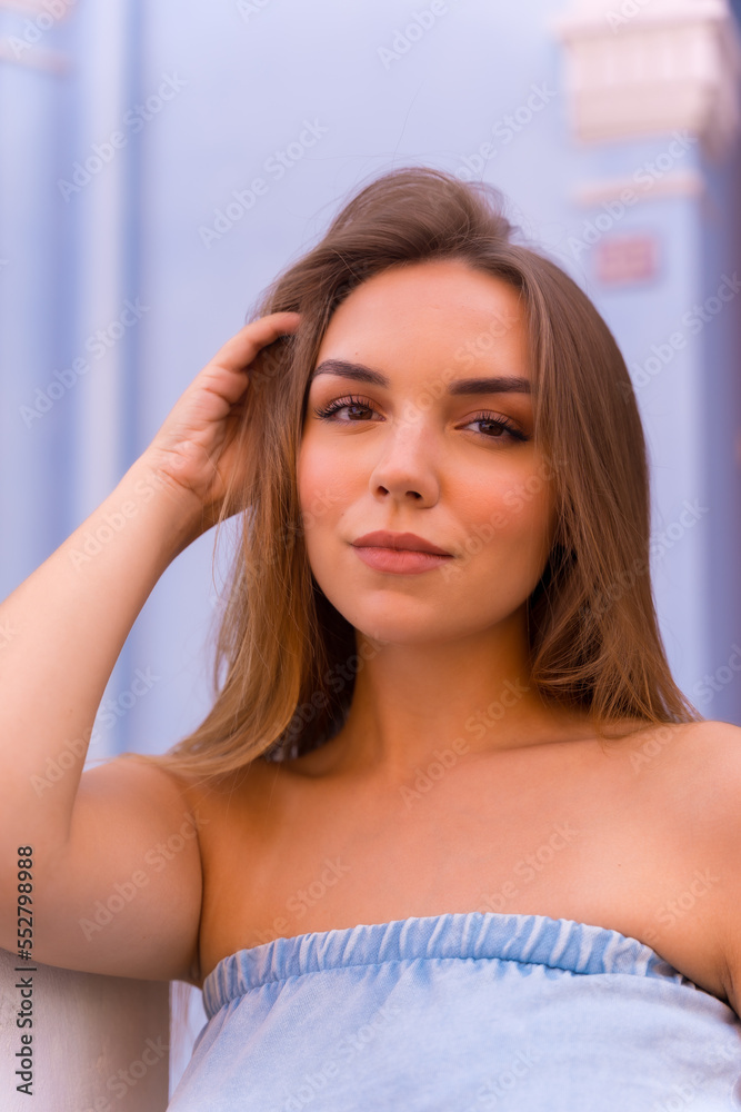 Fototapeta premium Summer lifestyle, portrait of attractive young blonde woman in blue dungarees smiling