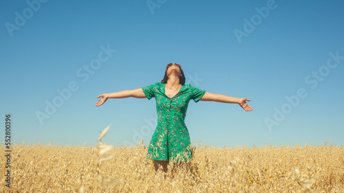 woman breathing fresh air with an azure blue sky in the background. Woman breathing fresh air with open arms in nature. Woman breathing calmly looking at the sky. Woman outdoors in nature © Pixel_Studio_8