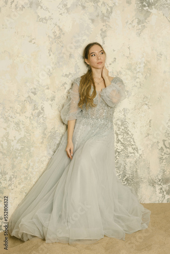 a girl in a dress on the sand against a shabby wall