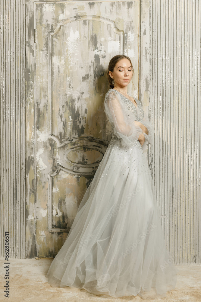 a girl in a dress on the sand on the background of a wall a girl in a dress on the sand on the background of a wall