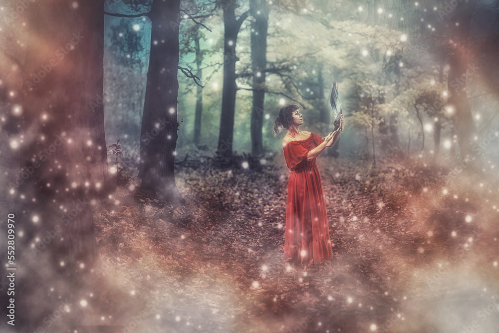 Fototapeta premium Shaman woman in deep mystical misty forest, with feathers fan with deer antler in hand. Feathers fan used for viewing during ceremonies.