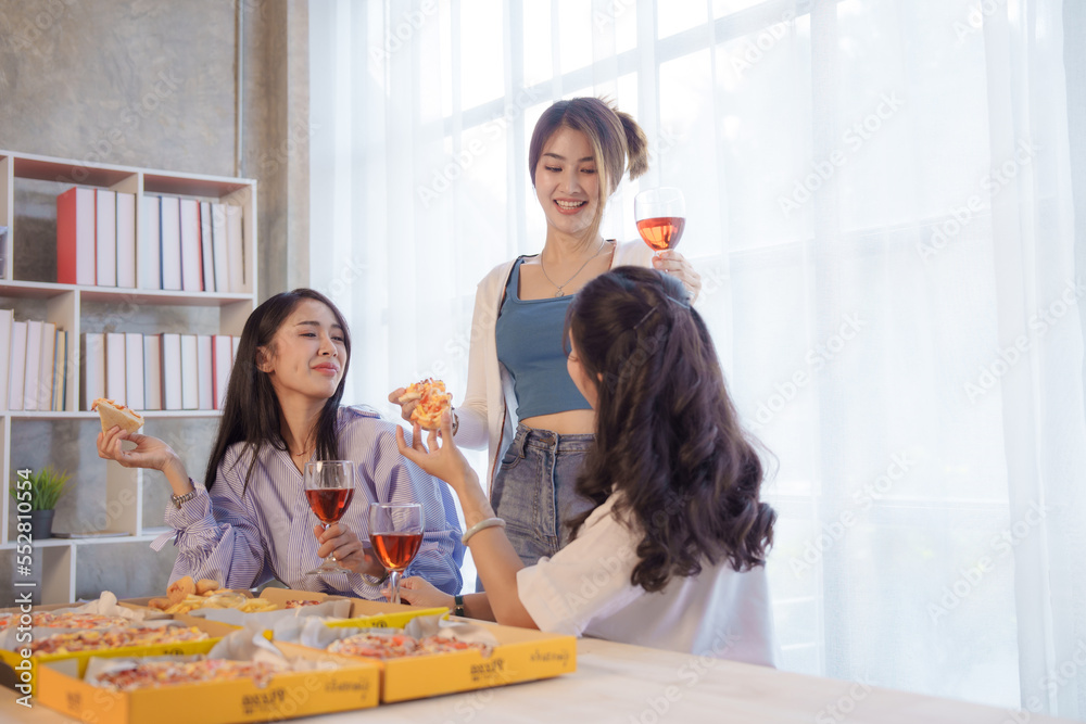 Group of young asian office girl friends having fun and celebrating pizza on table during party
