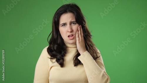 Portrait of young hipster woman 20s with tooth dental ache pain problem in mouth isolated on green screen background in studio
