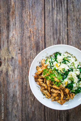 Fried chicken nuggets with white rice and spinach on wooden table 