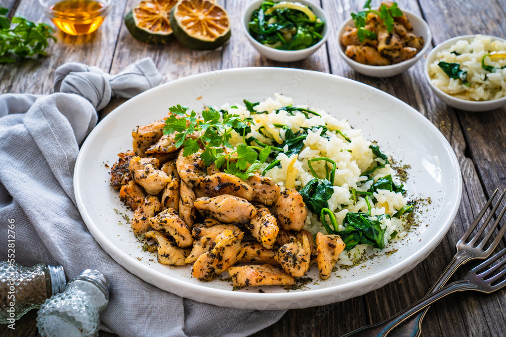 Fried chicken nuggets with white rice and spinach on wooden table

