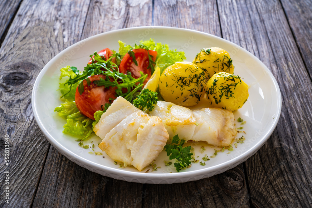 Fish dish - fried halibut with boiled potatoes and fresh vegetables on wooden table
Fish dish - fried halibut with boiled potatoes and fresh vegetables on wooden table