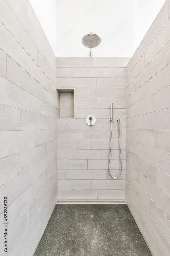 a walk in shower with gray tile flooring and white wall tiles on the