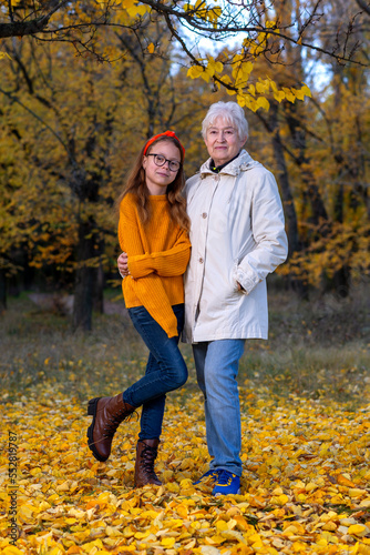 Grandmother and granddaughter in the autumn forest.