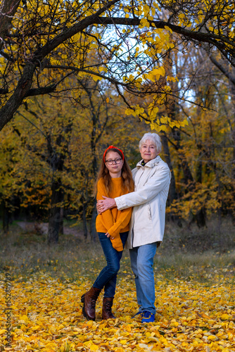 Grandmother and granddaughter in the autumn forest.