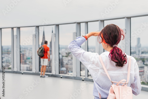 A tourist girl admires the scene on the panoramic touristic viewpoint at the top of a skyscraper in Cologne, with the cathedral in the background