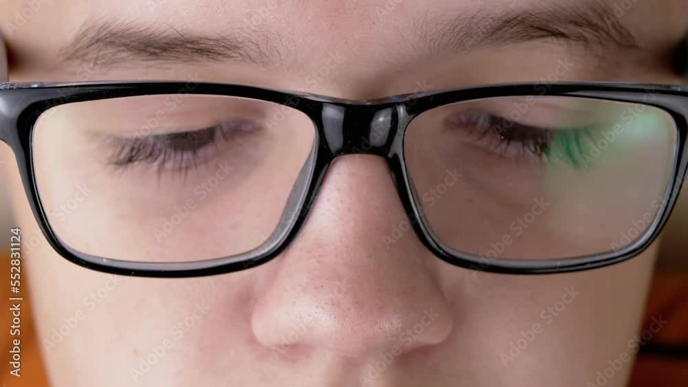 Close-up Part of the Face of a Child with Glasses Watching on Screen TV in Room. Boy with long eyelashes. Reflection glare light in glasses. Poor eyesight. Macro. Internet, reading, working online. Close-up Part of the Face of a Child with Glasses Watching on Screen TV in Room. Boy with long eyelashes. Reflection glare light in glasses. Poor eyesight. Macro. Internet, reading, working online.